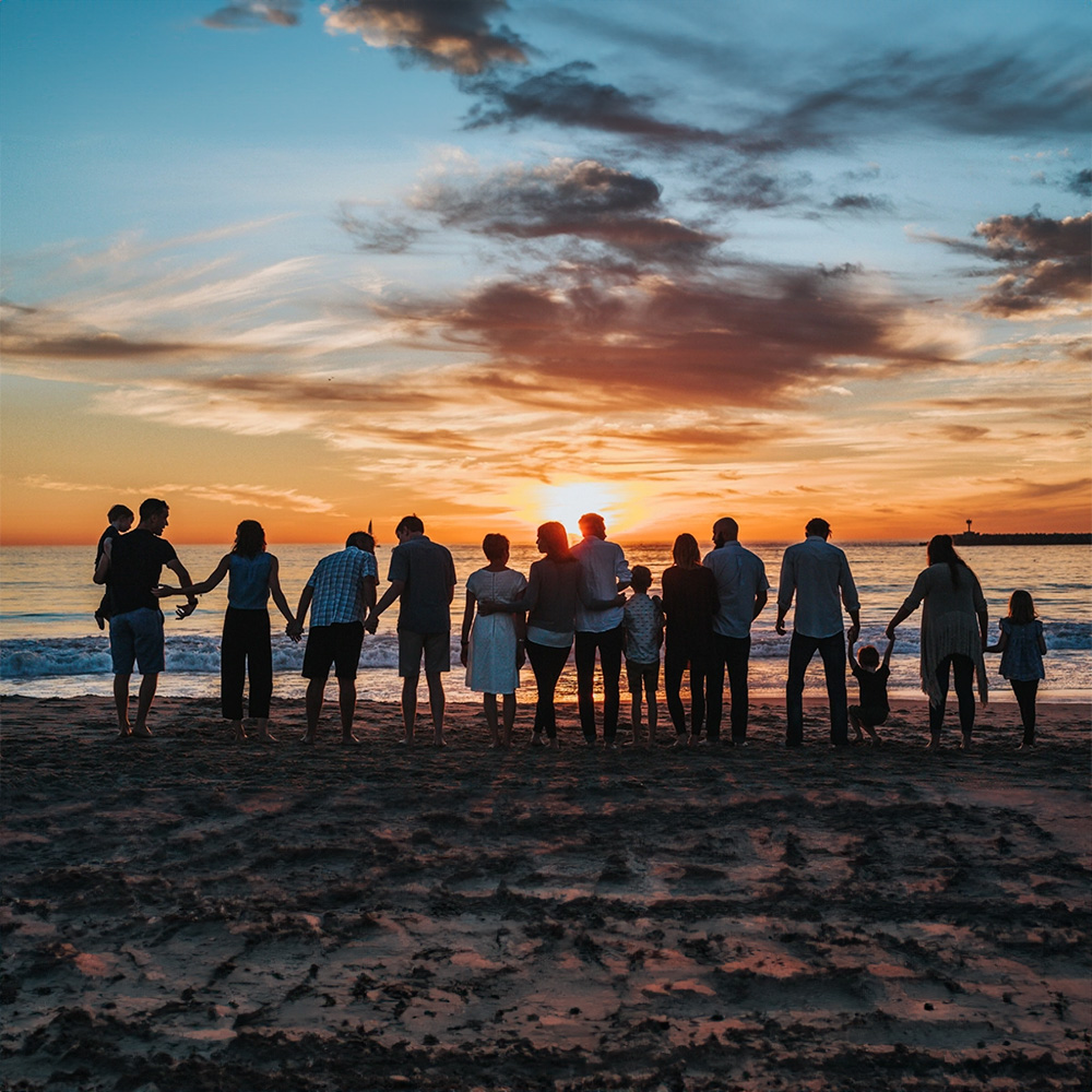 Gente en la playa al atardecer, disfrutando sus vacaciones.